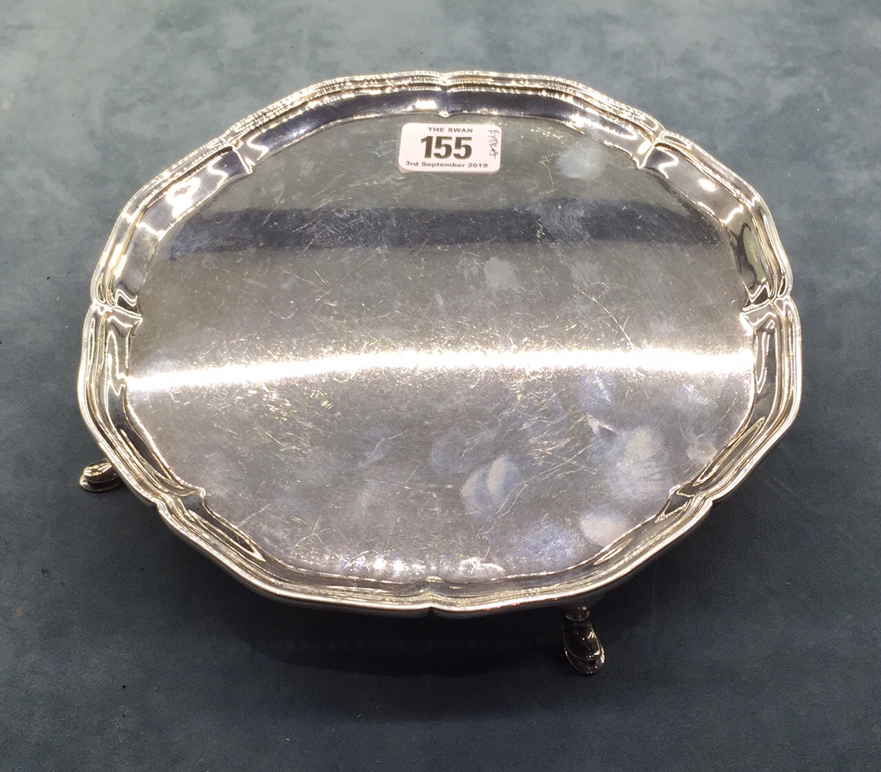 AN ENGLISH HALLMARKED SILVER CARD TRAY With a piecrust border, raised on four legs with hoof