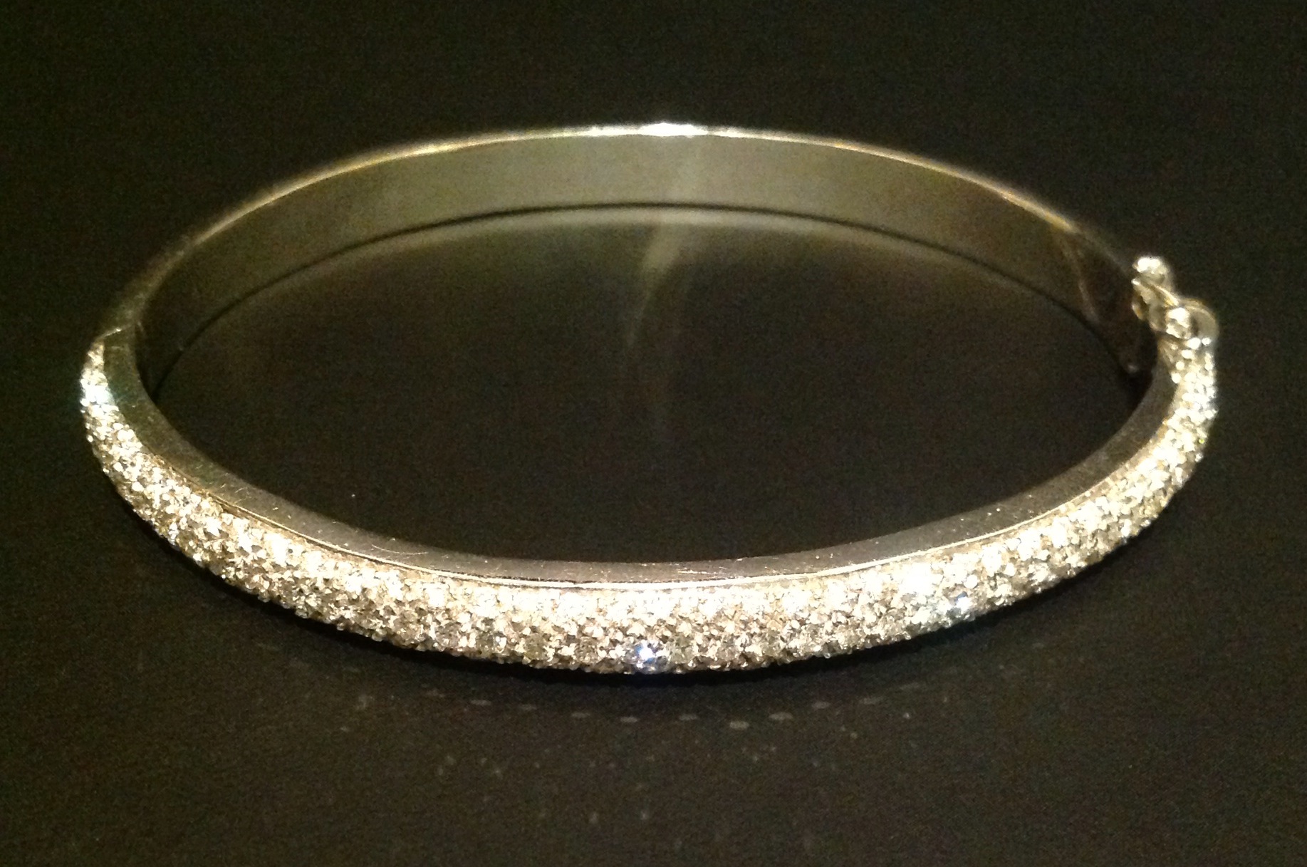 AN 18CT WHITE GOLD AND DIAMOND BANGLE Half pavé set with small round cut diamonds, hinged with