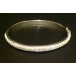 AN 18CT WHITE GOLD AND DIAMOND BANGLE Half pavé set with small round cut diamonds, hinged with