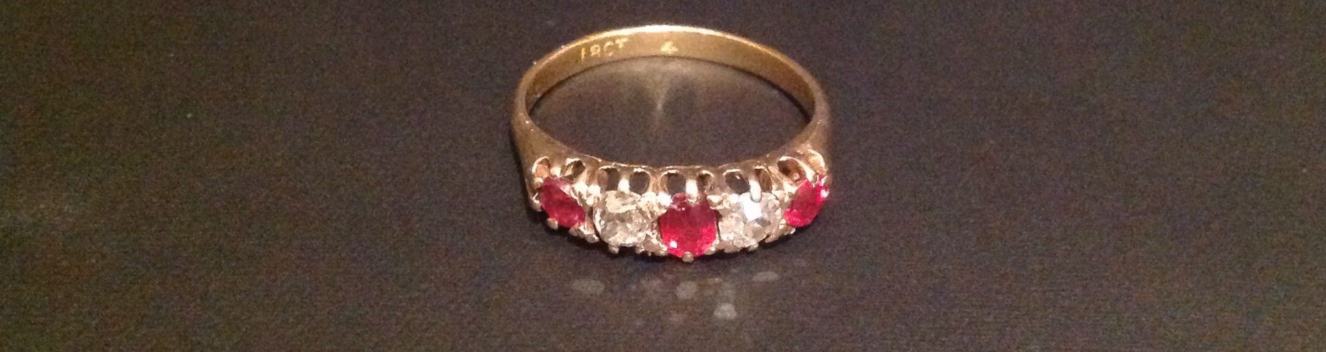 AN EARLY 20TH CENTURY 18CT GOLD, RUBY AND DIAMOND FIVE STONE RING The three round cut rubies,