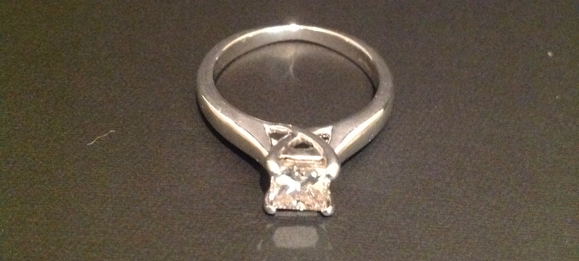 AN 18CT WHITE GOLD PRINCESS CUT DIAMOND SOLITAIRE RING The diamond claw set and flanked by solid