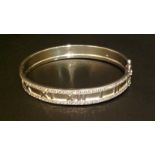 AN 18CT WHITE GOLD AND DIAMOND BANGLE In the style of Cartier 'Atlas', having embossed Roman