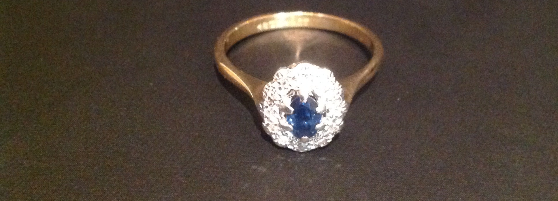 AN 18CT GOLD, SAPPHIRE AND DIAMOND SET RING The oval sapphire within an illusion set diamond border,