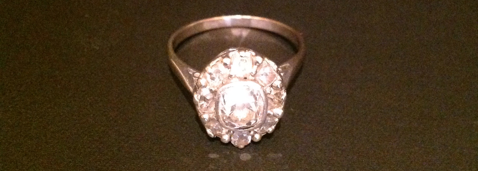 AN UNMARKED WHITE GOLD AND DIAMOND CLUSTER RING The central collet set cushion cut diamond, in a