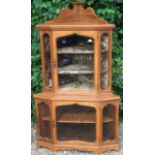 AN EDWARDIAN WALNUT TWO TIER GLAZED CORNER CABINET Raised on shaped bracket feet.