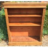 AN OAK FLOORSTANDING OPEN BOOKCASE With adjustable shelves and reeded columns, raised on a plinth