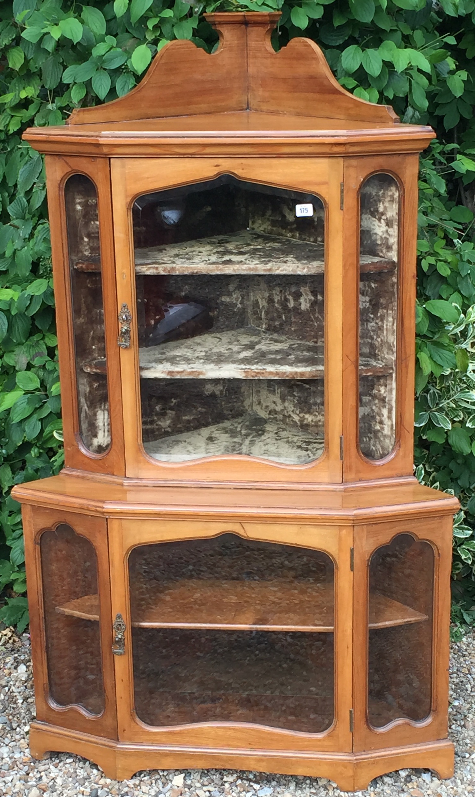 AN EDWARDIAN WALNUT TWO TIER GLAZED CORNER CABINET Raised on shaped bracket feet.