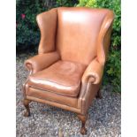 A LARGE GEORGIAN STYLE TAN LEATHER WING ARMCHAIR Raised on ball and claw feet. (h 113cm x w 86cm x d
