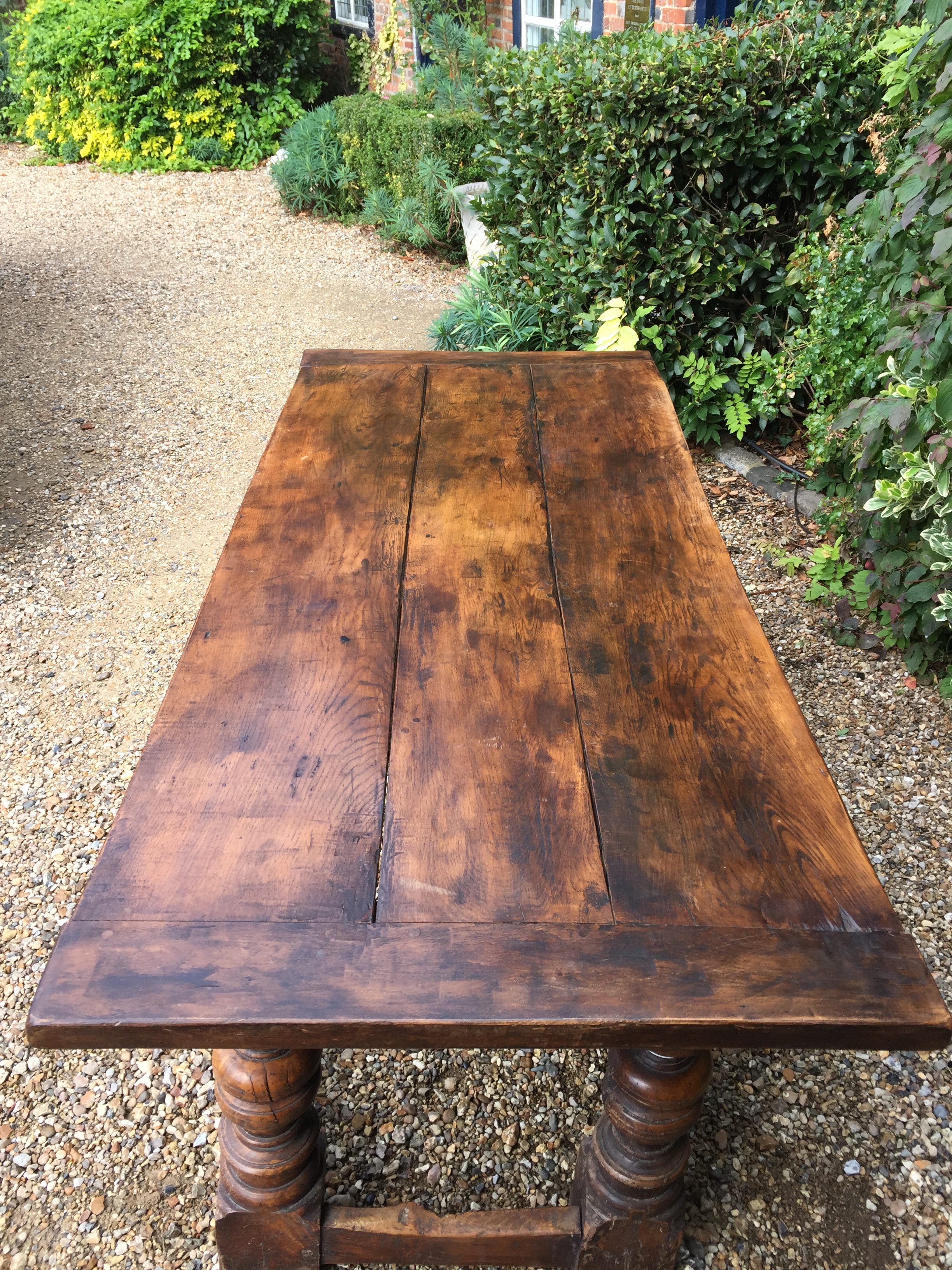 A 17TH CENTURY DESIGN OAK TABLE With a three plank top, raised on heavy turned square legs, joined