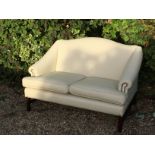 A MAHOGANY HUMPBACK TWO SEATER SETTEE Upholstered in a beige fabric and raised on square legs. (h
