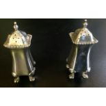 A PAIR OF EDWARDIAN HALLMARKED SILVER PEPPERETTES With convex waist and gadrooned edges, resting