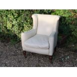 A LATE VICTORIAN WINGBACK UPHOLSTERED ARMCHAIR Raised on turned mahogany legs, terminating at