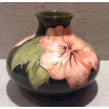 MOORCROFT, A POTTERY VASE With a tubelined decoration, depicting coral hibiscus leaves on a green