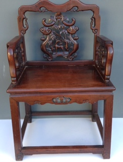 AN EARLY 20th CENTURY CHINESE PADOUK WOOD OPEN ARMCHAIR With heavily carved back and solid seat