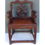 AN EARLY 20th CENTURY CHINESE PADOUK WOOD OPEN ARMCHAIR With heavily carved back and solid seat