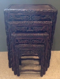 A NEST OF FOUR EARLY 20th CENTURY CHINESE HARDWOOD TABLES Carved in high relief with dragons and