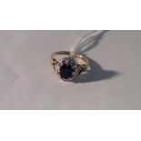 A 9CT GOLD, SAPPHIRE AND DIAMOND RING The oval brilliant cut blue sapphire within frame inset with