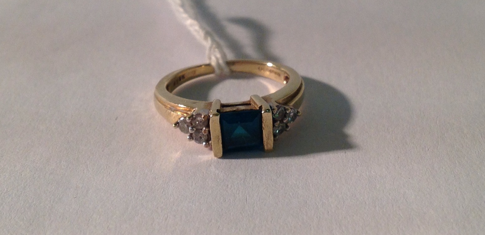 A 9CT GOLD, PASTE AND DIAMOND RING The square step cut faux emerald channel set, between yellow gold