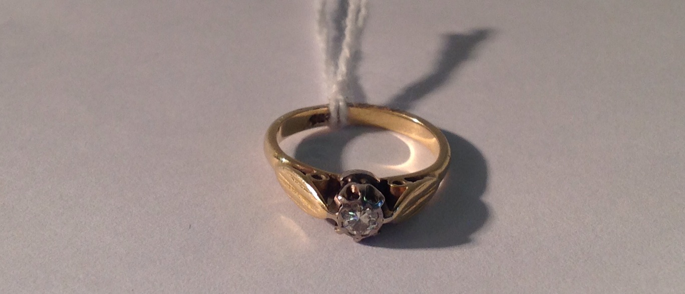 AN EARLY 20TH CENTURY 18CT GOLD AND DIAMOND SOLITAIRE RING The round brilliant cut diamond in a tall