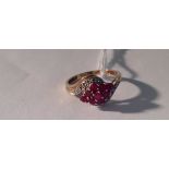 A 9CT GOLD, RUBY AND DIAMOND HALF TWIST RING The nine round brilliant cut rubies arranged in a