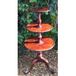 AN EARLY VICTORIAN MAHOGANY THREE TIER DUMB WAITER  With dished rims and centred with a turned