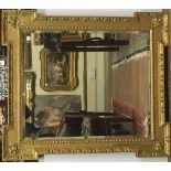 IN THE MANNER OF WILLIAM KENT, A LARGE GILT FRAMED MIRROR Having square corners with recessed sides,