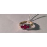 A 9CT GOLD, RUBY AND DIAMOND SET DRESS RING With central oval brilliant cut ruby between two smaller