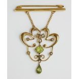 An Edwardian peridot and split pearl gold pendant brooch, with a claw set peridot to a scrolling