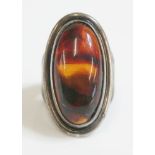 A sterling silver Danish modernist ring, by Hermann Siersb›l with an oval cabochon amber, rub set to