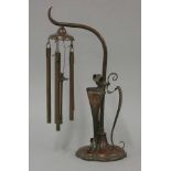 A copper stand with scrolled mounts supporting wind chimes, after WAS Benson, 35cm high