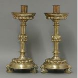 A pair of Victorian Gothic brass candlesticks, in the Medieval Revival style, raised on lion