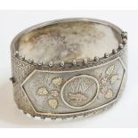 A Victorian silver hinged bangle, decorated with a central panel of a bird and flowers, with two