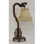 An early 20th century Chinese hardwood table lamp, carved with a dragon head, with fret cut