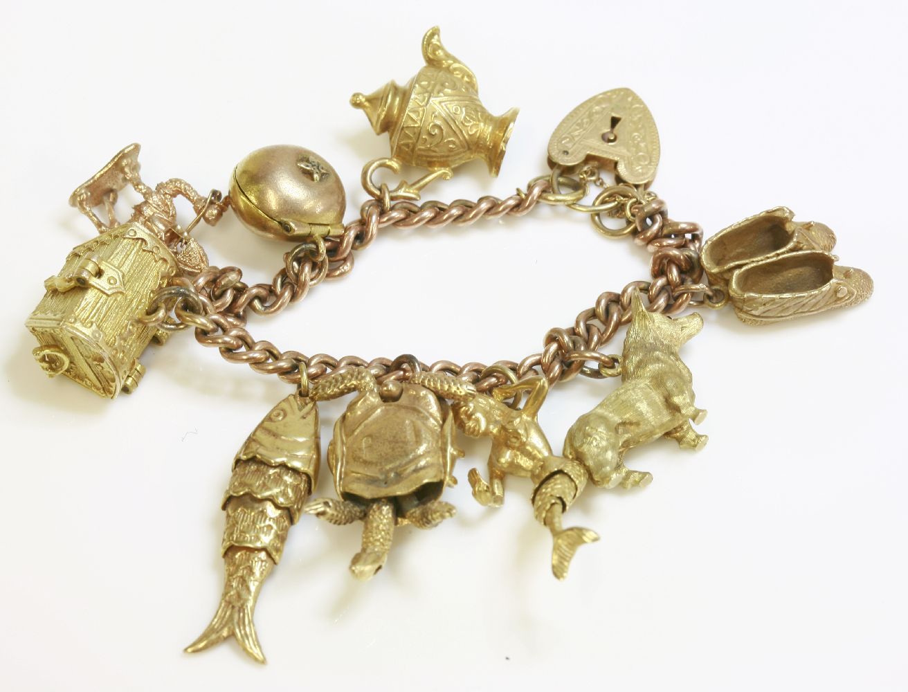 A gold curb link charm bracelet, marked 9ct, hung with seven 9ct gold charms, including a corgi