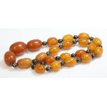 A single row of graduated oval amber beads, with piqu‚ style spacer beads