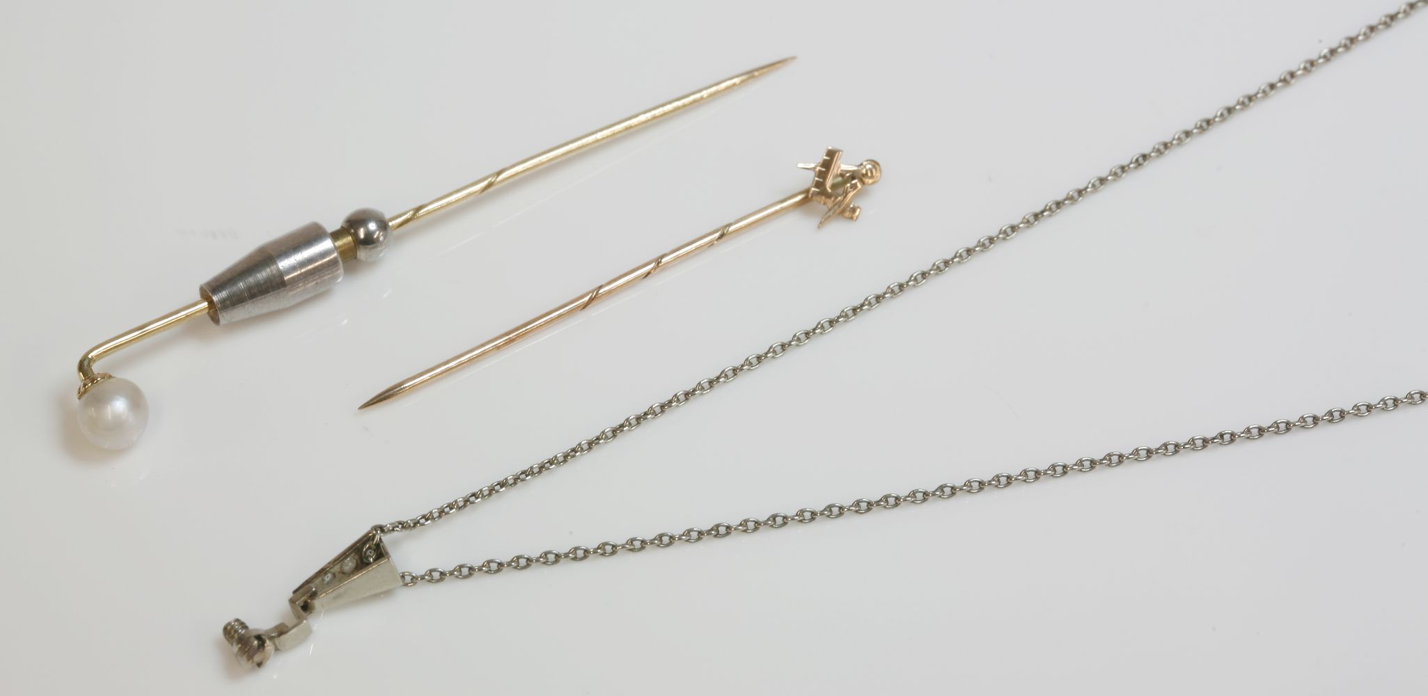 A gold stick pin, mounted with a pearl, pearl untested, another gold Masonic stick pin, and a