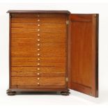 A mahogany collector's cabinet,late Victorian, the arabesque panelled door with thirteen slides