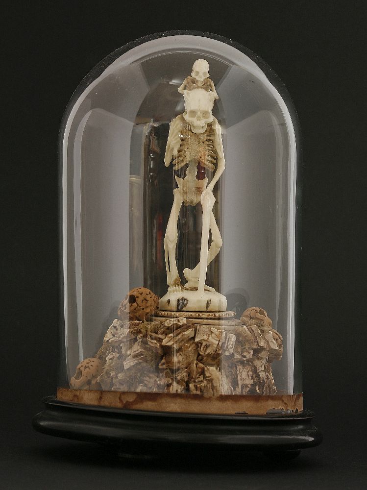 A bone and cork group,late 19th century, depicting a skeleton holding a walking stick, with a