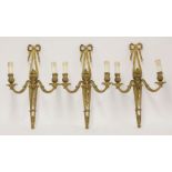 Three gilt bronze twin branch wall lights,the foliate scrolled arms on tapering, pierced, ribbon-