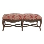 A Victorian walnut stool,of serpentine form with a carved frieze and scrolled legs,124cm long49cm