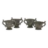A set of four lead urns,each with eagle handles and winged masks above a gadrooned body, on fleur-