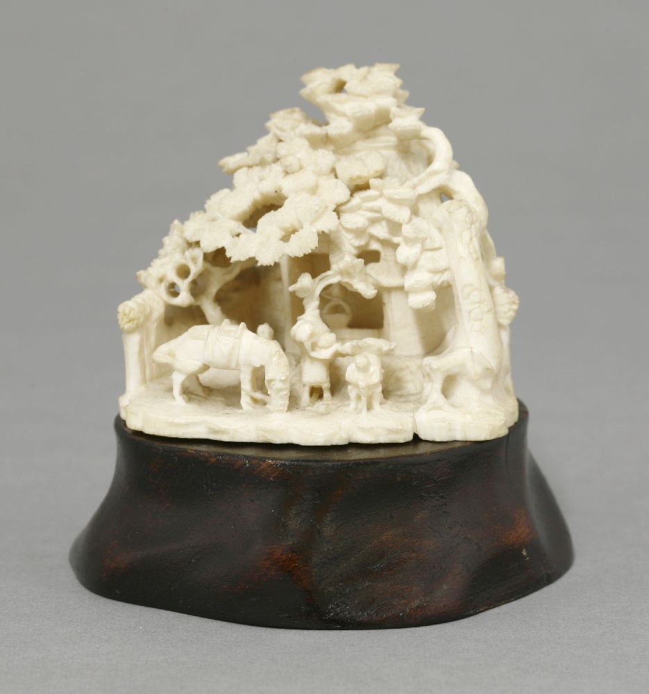 An ivory Group, c.1880, of a thatched wellhead overgrown with pine, the foreground with figures