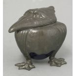 A pewter 'Grotesque Bird' inkwell, with a pottery well, raised on three claw feet, 11cm high