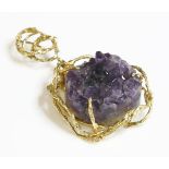 An 18ct gold amethyst geode pendant, c.1970,of open molten form, a circular section of amethyst