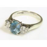 A 9ct white gold, three stone aquamarine and diamond ring,an oval mixed cut aquamarine, with a