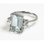 A white gold single stone aquamarine ring with diamond set shoulders,an emerald cut aquamarine, four