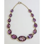 A late Victorian amethyst and gold rivière,with a series of graduated oval mixed cut amethysts,