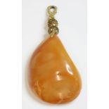 A free-form butterscotch amber pendant,55 x 39 x 22.3mm, strung on to pale yellow thread with two