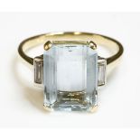 A single stone aquamarine ring,with diamond set shoulders, a step cut aquamarine four claw set at