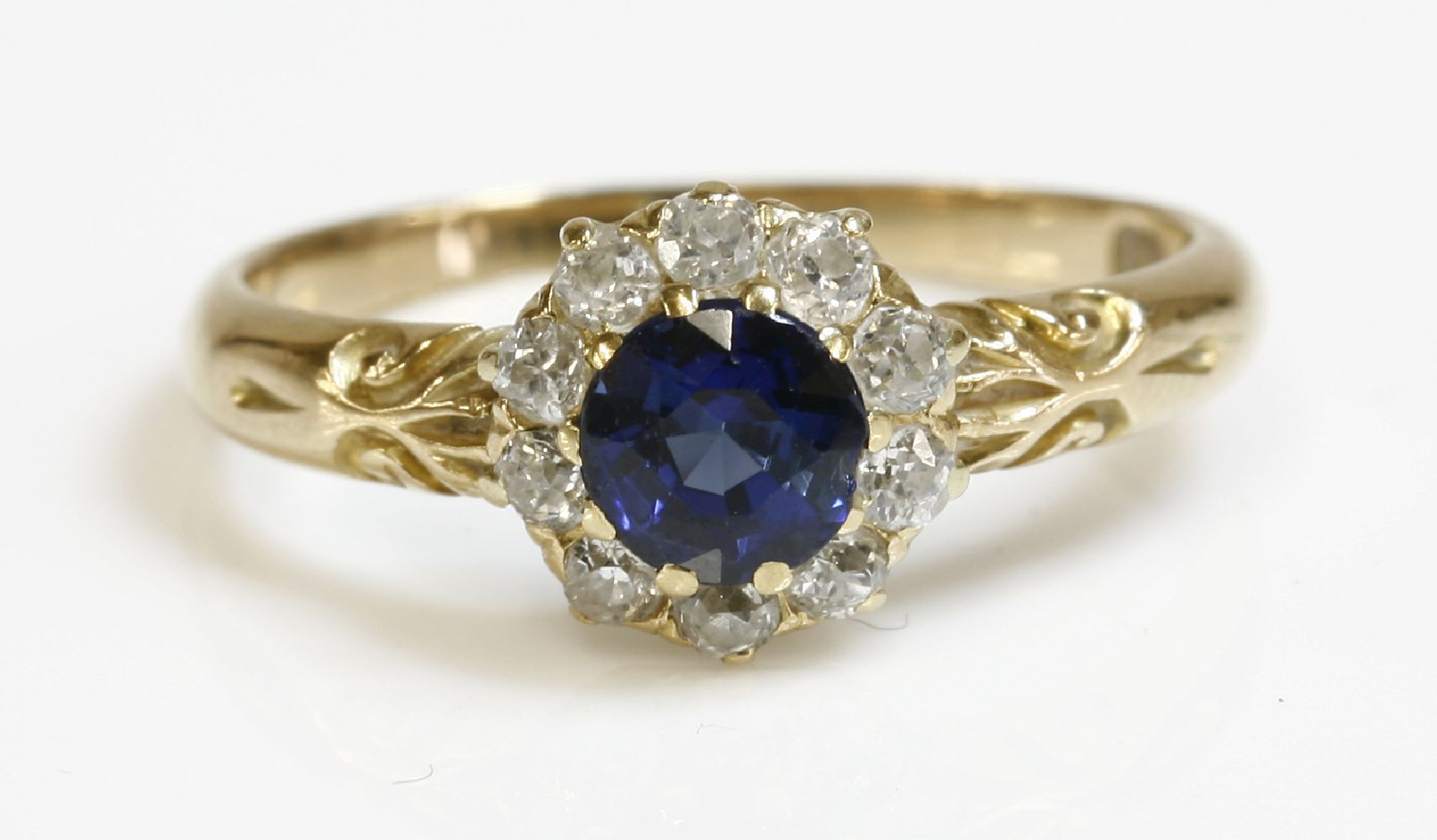 An Edwardian sapphire and diamond circular cluster ring,with a circular mixed cut sapphire, claw set